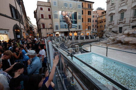 Fontana di Trevi senza acqua per il restauro, turisti lanciano monete in una vasca