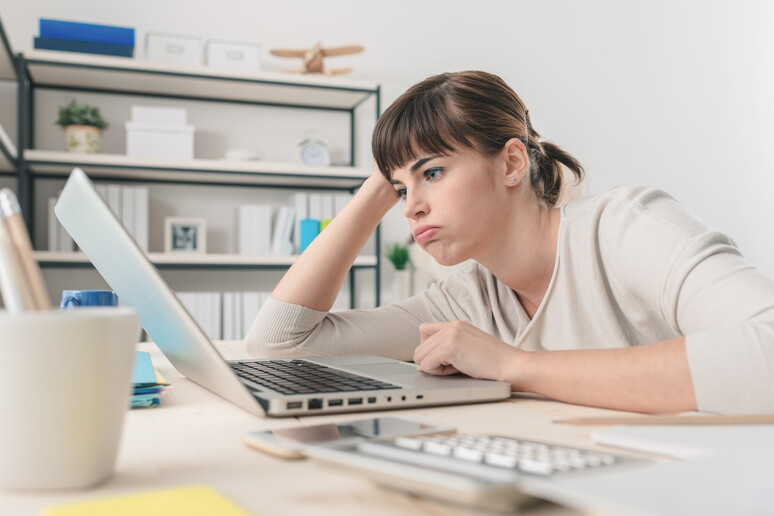 Una donna annoiata al computer foto iStock. - RIPRODUZIONE RISERVATA